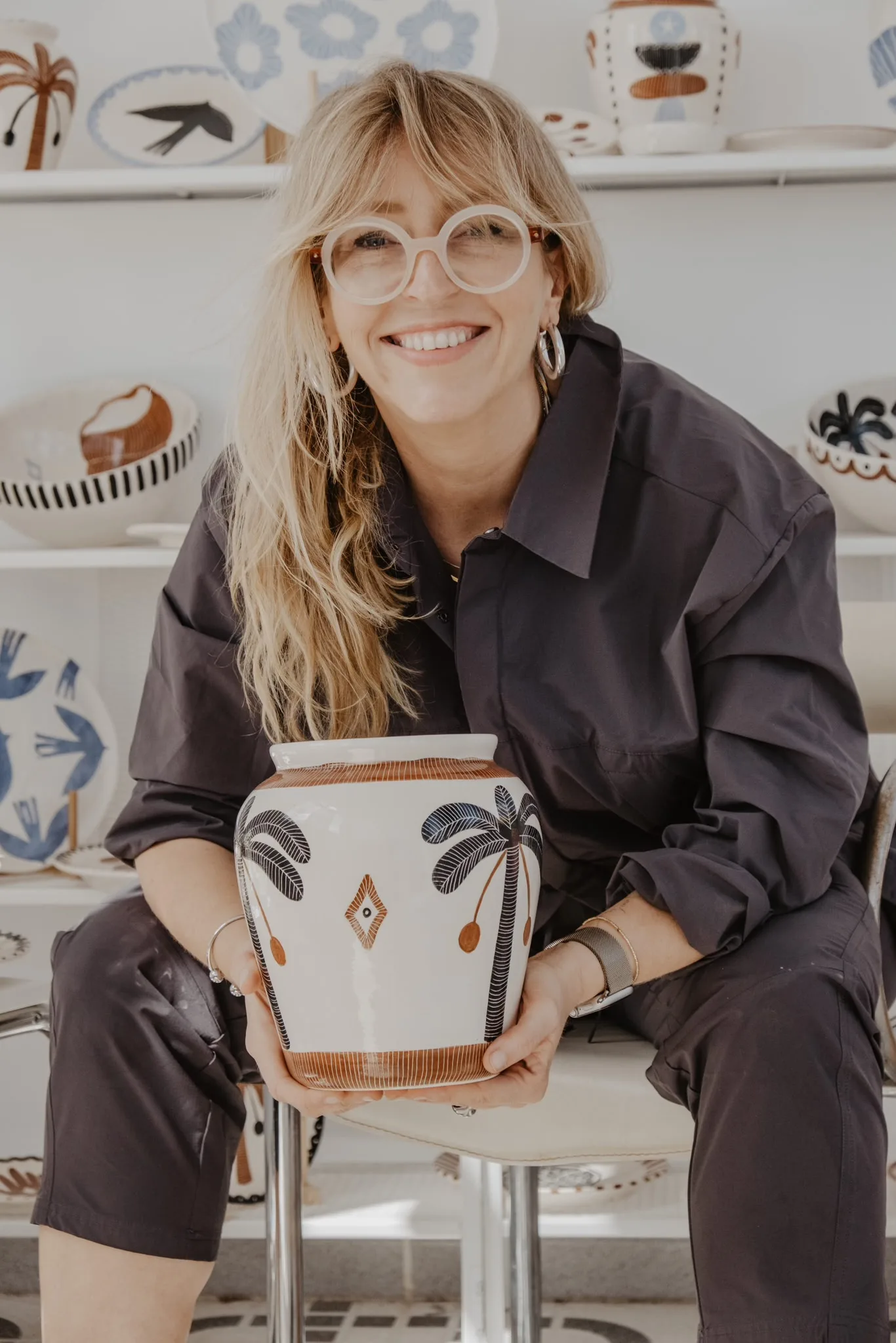 Anna Ciok seated in the studio with a hand-painted vase