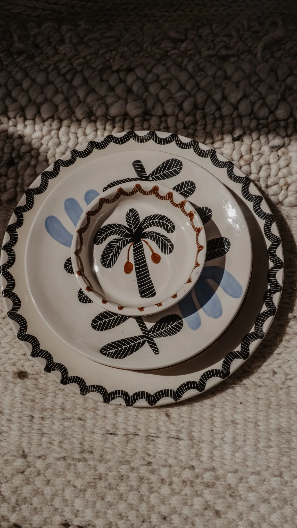 A palm-motif plate in shadow on a woven rug