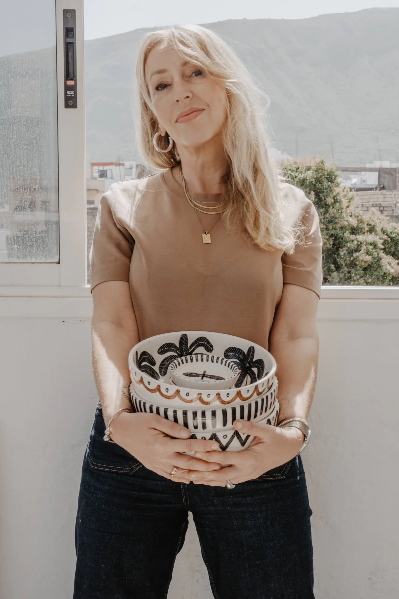 Anna Ciok standing near a window with a hand-painted bowl