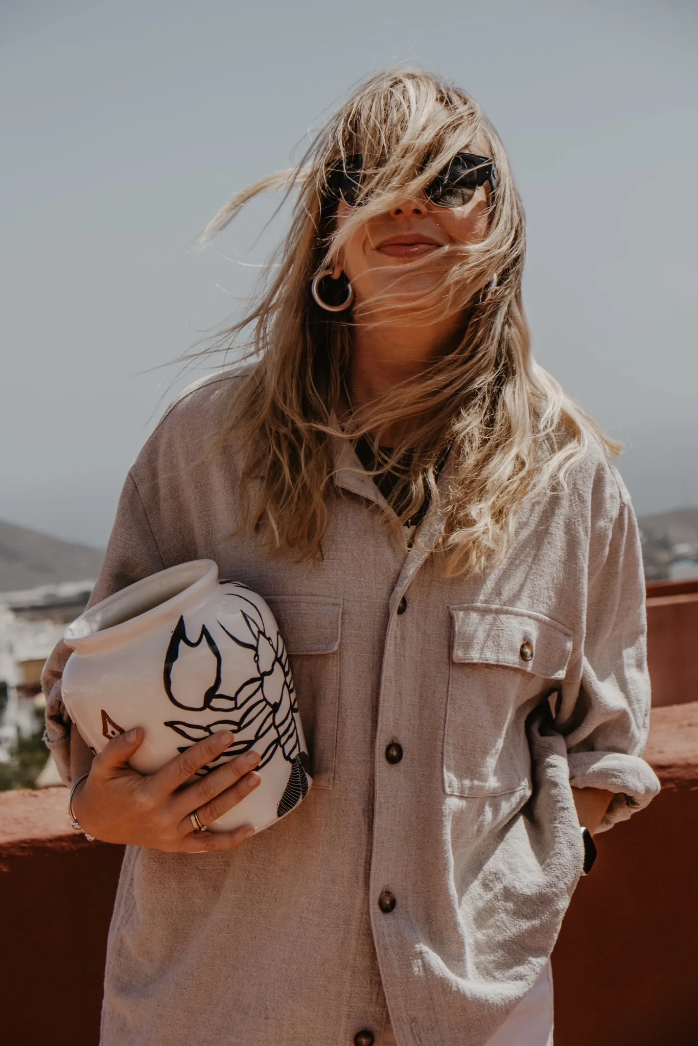 Anna Ciok holding a hand-painted vase in the wind